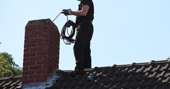 A chimney sweep at work atop a roof
